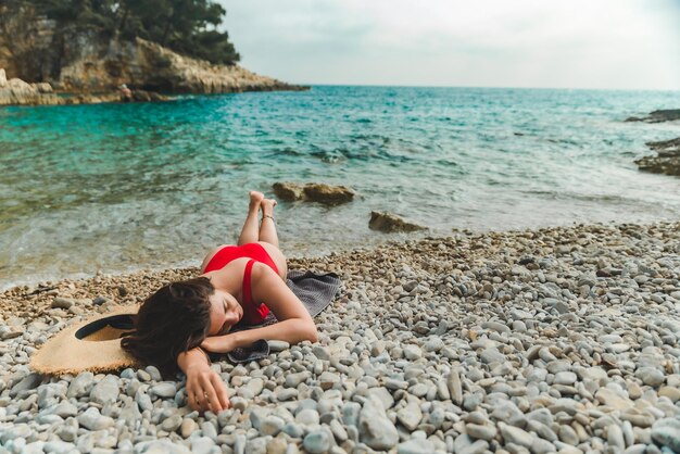 Woman laying on blanket at sea beach copy space