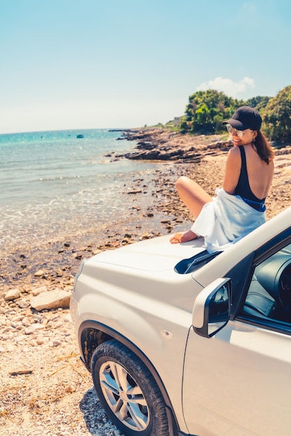 Woman laying at car hood with view of sea summer beach