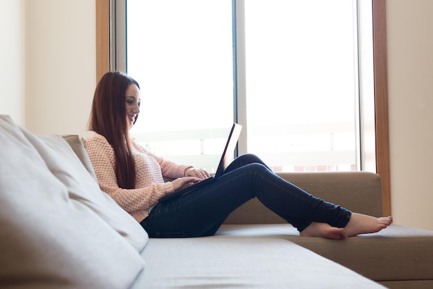 Woman laying down on couch with a laptop