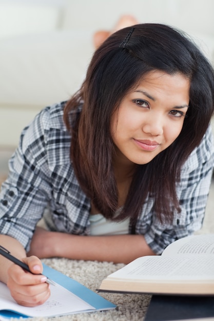 Woman laying on the floor while writing on a notebook