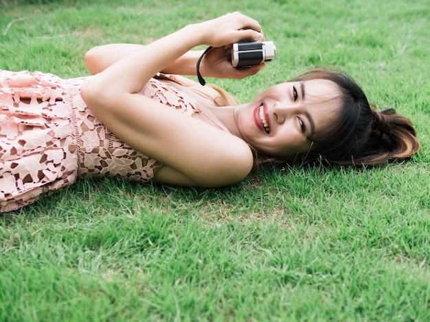 Foto una donna sdraiata sull'erba con una macchina fotografica