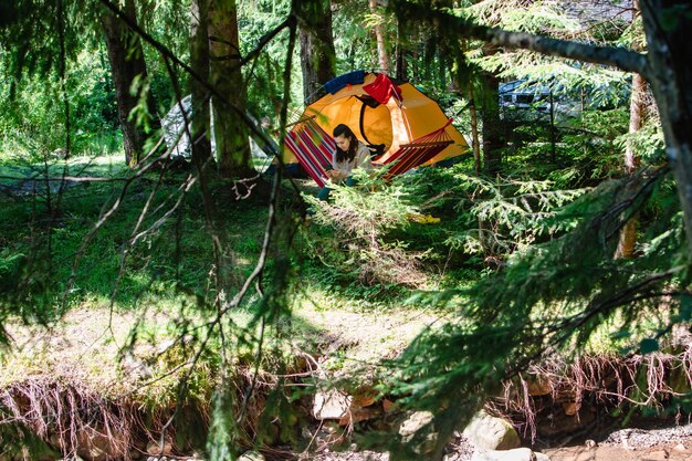 Woman laying in the hammock tent and car on background