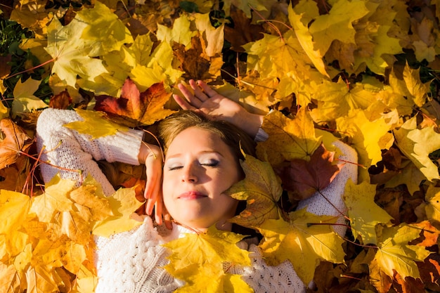 Woman laying in maple leaves in the park