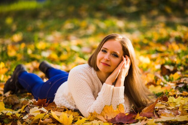 Woman laying in maple leaves in the park