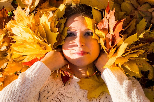 Photo woman laying in maple leaves in the park