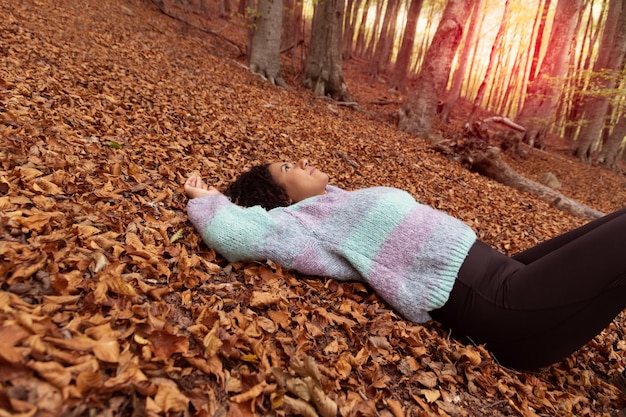 A woman laying on a pile of leaves in a forest