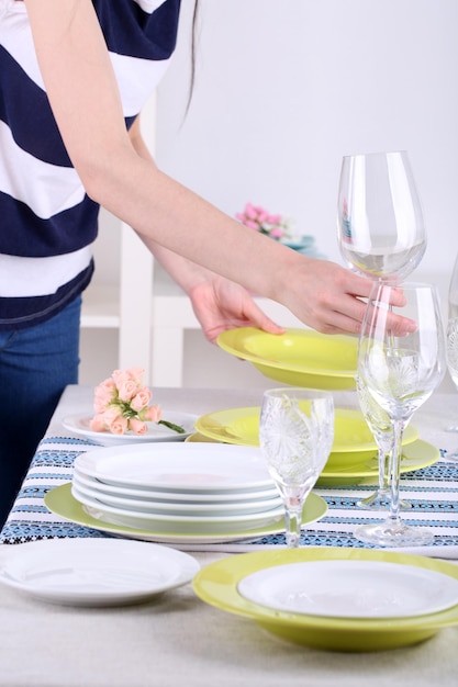 Woman laying table in room