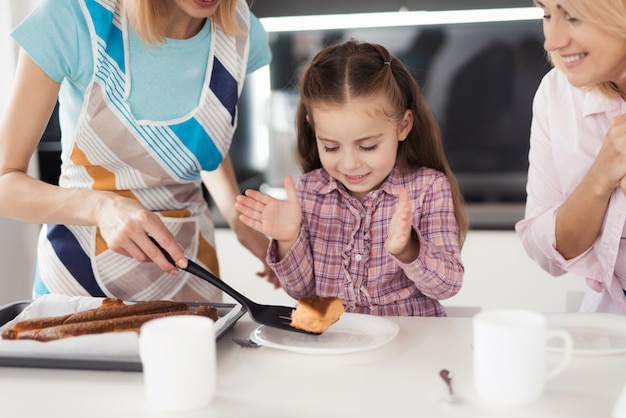 Женщина отдает кусочек торта своей дочери.