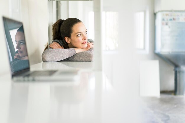 Woman leaning on desk with laptop