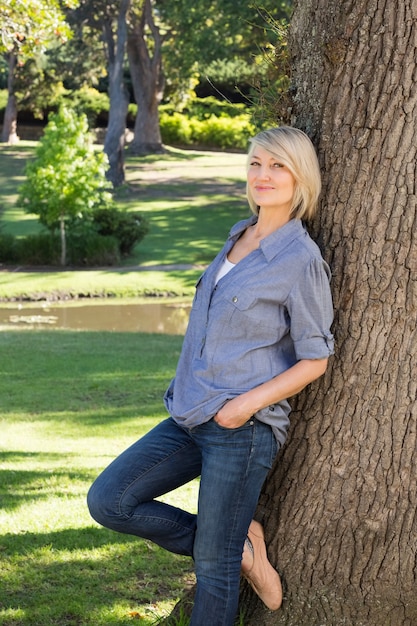 Woman leaning on tree trunk in park