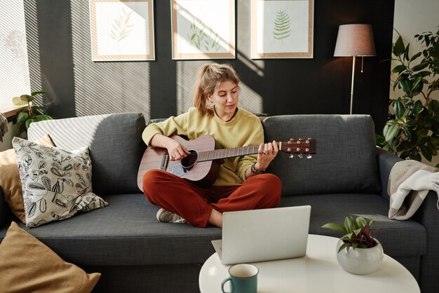 Woman learning to play guitar online