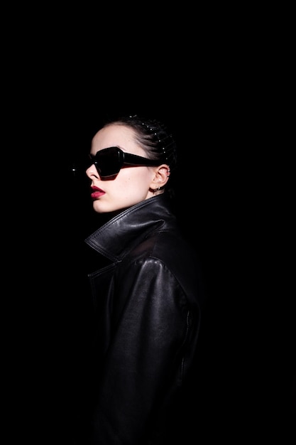 woman in leather coat and black sunglasses black background High quality photo