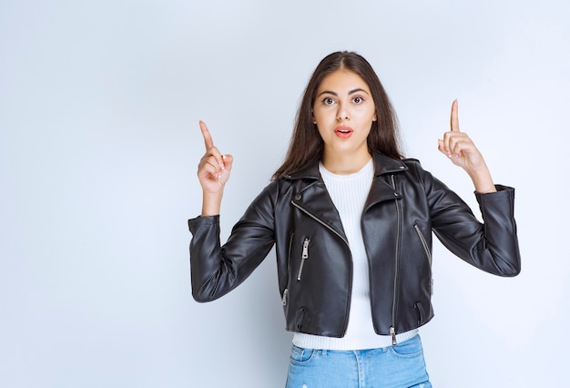 Woman in leather jacket pointing at something above