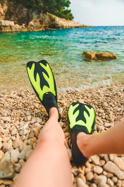 Gambe di donna in pinne in spiaggia mare sullo sfondo