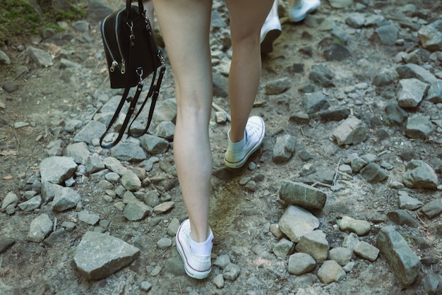 Woman legs goes on a rocky road. Hiking into the mountains. Closeup