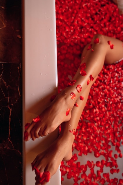 Woman legs in a rose petals bath