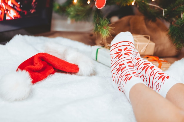 Foto le gambe della donna in calzini si avvicinano alla cartolina d'auguri dell'albero di natale