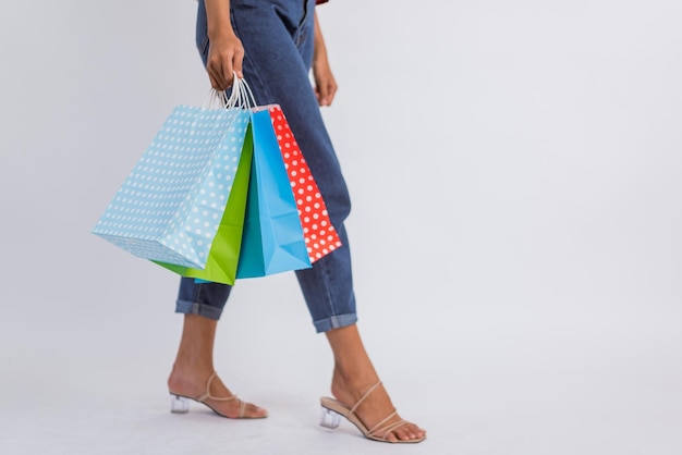 Photo woman legs standing with heels while bring the shopping bags on isolated background