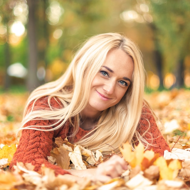 Woman lies down on leaves at the autumn park