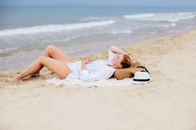 写真 海岸の砂の上に女性が横たわっています ⁇