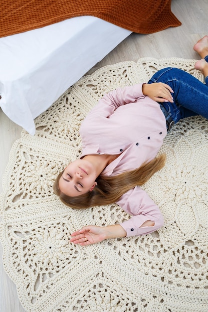 Foto una donna giace su un tappeto vicino al letto un tappeto fatto a mano fatto a mano con fili spessi fatti a mano un tappeto fatto a mano con fili beige giace sul pavimento