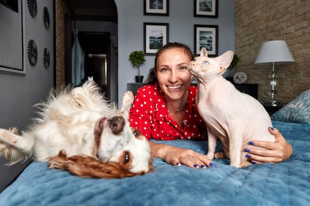 A woman lies on a sofa with a cat and a dog Love for pets concept