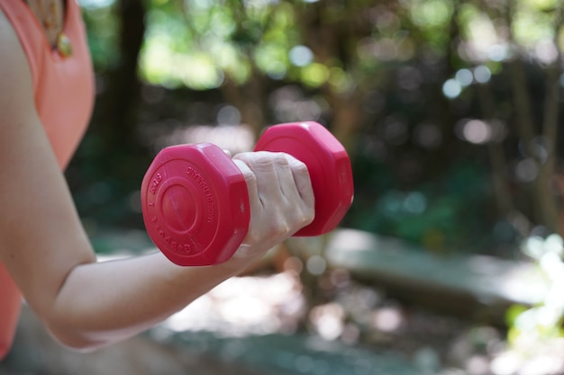 A woman lifting a dumbbell to exercise in the natural background