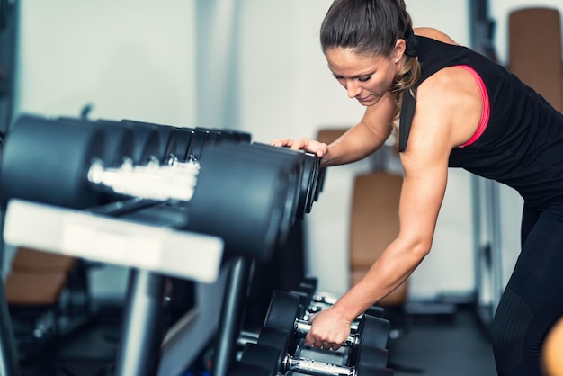 Foto donna che solleva un manubrio dal rack in palestra