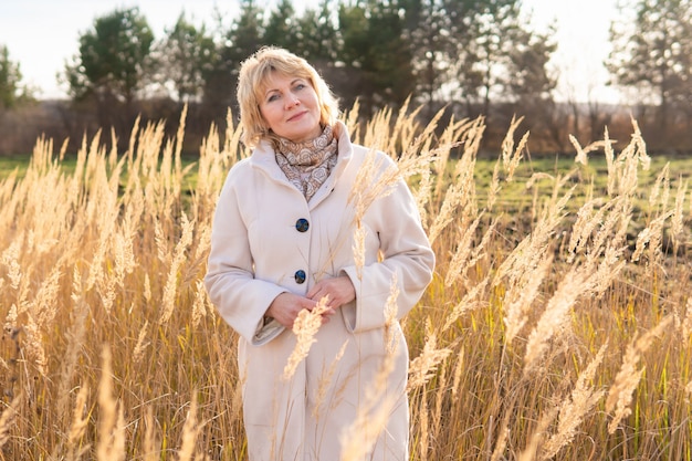 A woman in a light coat walks in nature in autumn