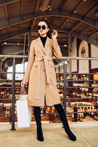 Woman in a light woolen coat and shopping bag