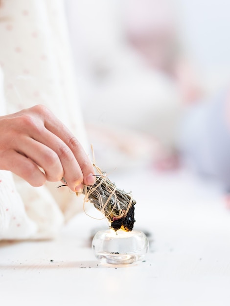 Woman lighting a smudge kit with herbal stick natural elements for cleansing environment from