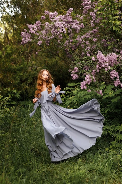 Woman in lilac dress in the garden at lilac summer