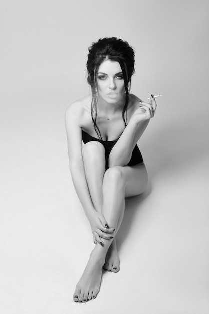 woman in lingerie sitting on the floor smoking