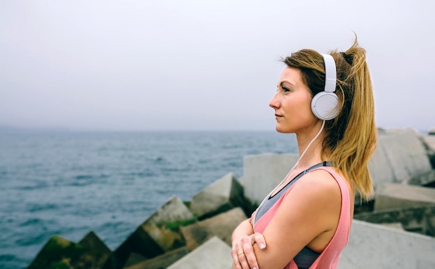 Foto donna che ascolta musica sulla spiaggia contro il cielo