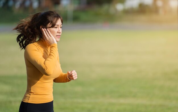 Woman listening music on earphones while running in the park