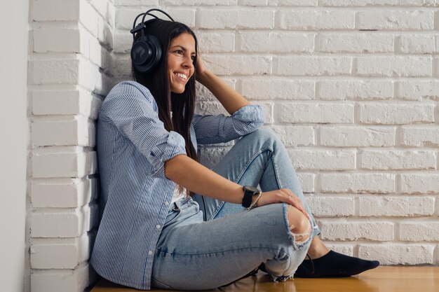 Woman listening music in headphones in room