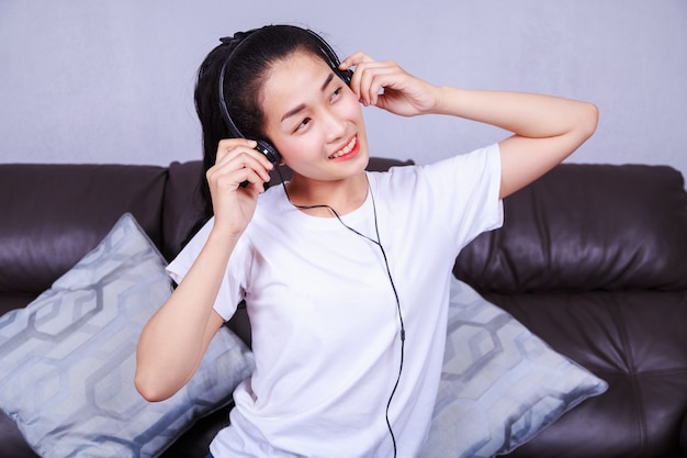 woman listening to music in headphones on sofa at home