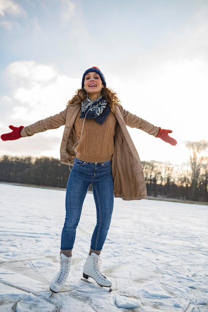 Photo woman listening to music and ice skating on frozen lake