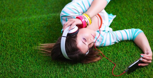 Woman listening to the music lying on grass