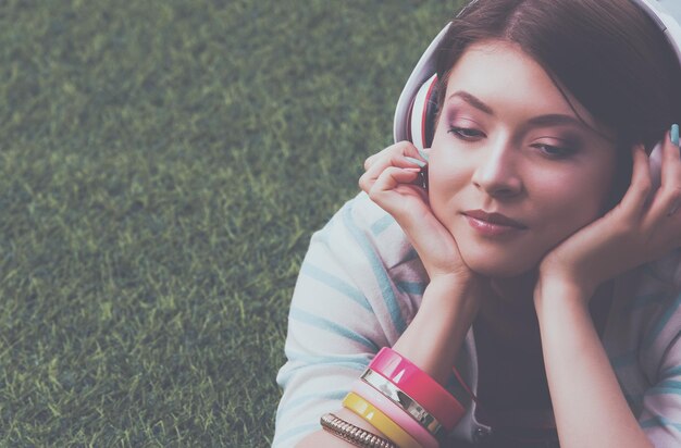 Woman listening to the music lying on green grass