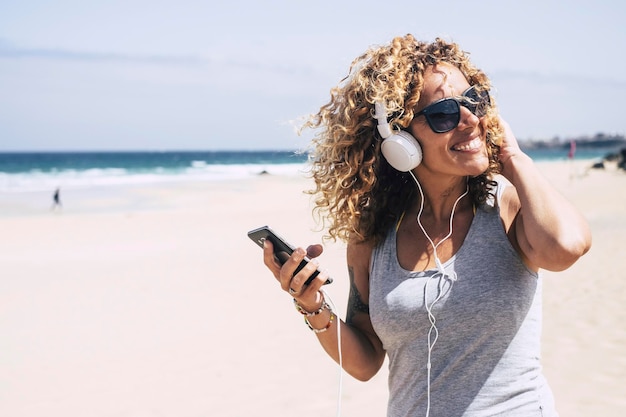 Foto donna che ascolta musica con le cuffie sulla spiaggia