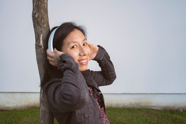 Woman listening to music on a tree in the street