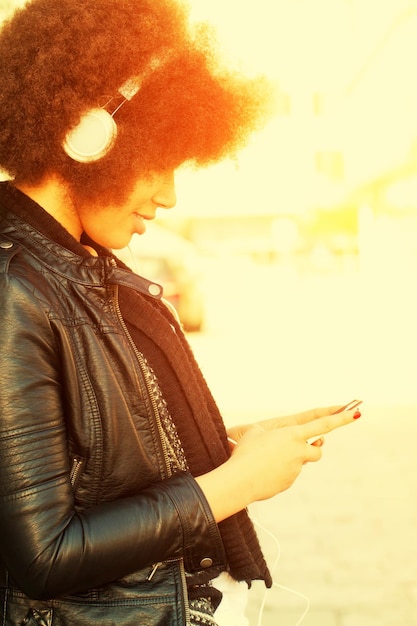 Photo woman listening music while using mobile phone in city