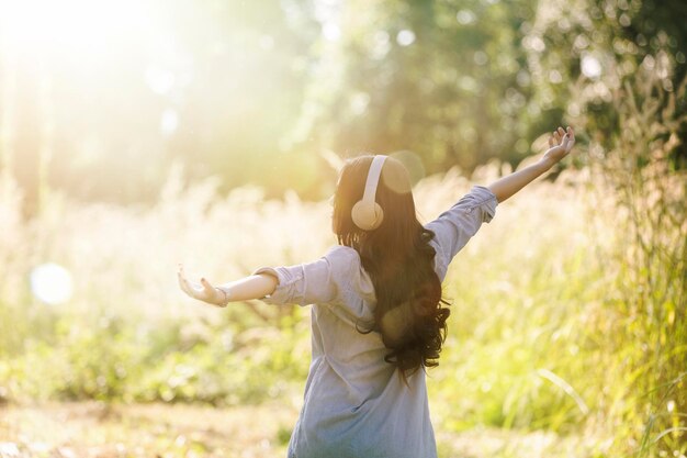 写真 植物の横を歩きながら音楽を聴いている女性