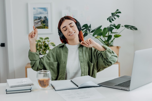 Donna che ascolta musica con cuffie wireless concetto di riposo durante lo studio online a casa