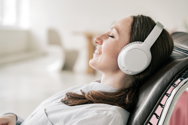 woman listens to an audiobook and a playlist in wireless Bluetooth headphones on the sofa relaxing