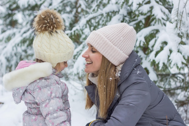 woman and little daughter are hugging in snowy fotest