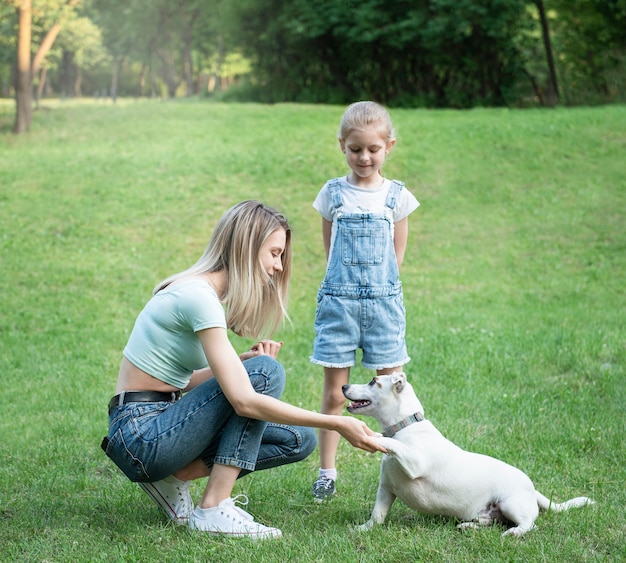 Woman and little girl playing with a dog breed Jack Russell Terrier