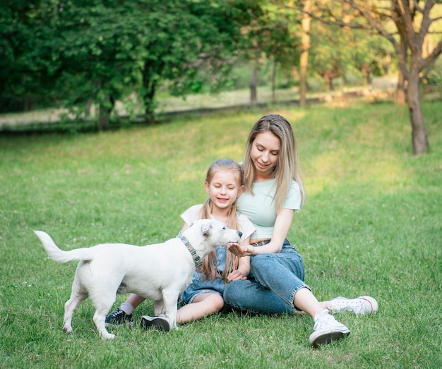 Woman and little girl playing with a dog breed Jack Russell Terrier