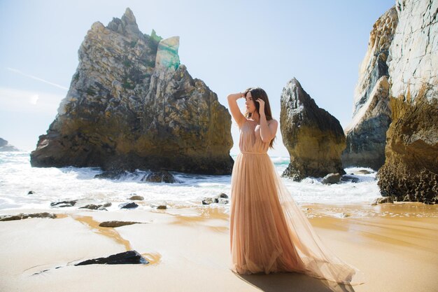 Woman in long dress near rocks and ocean